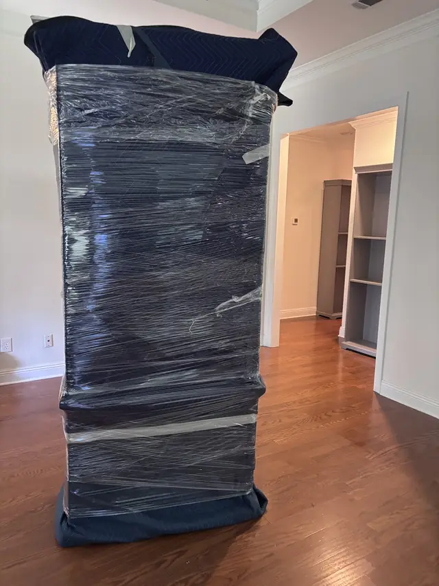 Cabinet shrink-wrapped with blankets on a hardwood floor