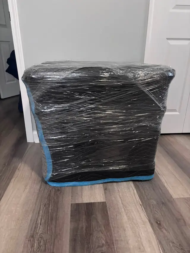 Dresser wrapped in black plastic on a hardwood floor