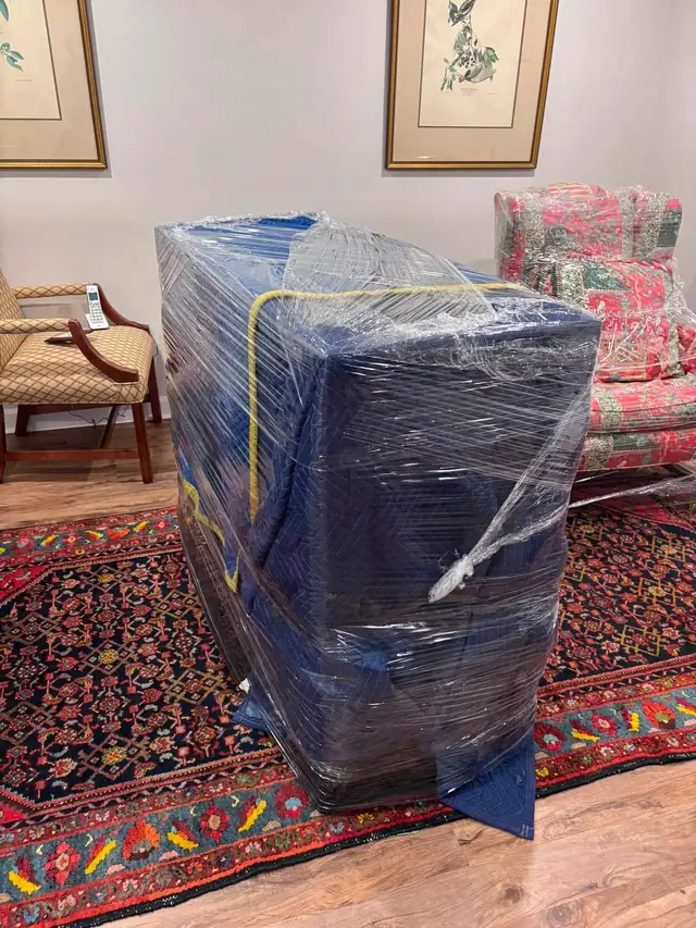 Dresser wrapped in blankets and plastic on an oriental rug