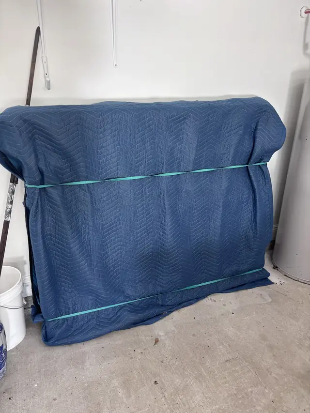 Furniture wrapped in a blue pad and strapped