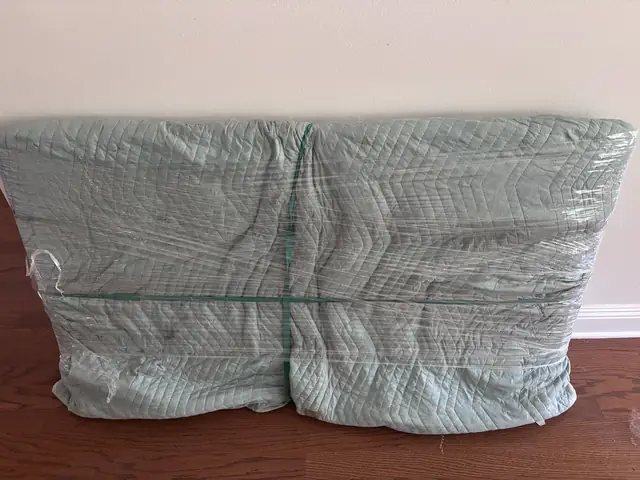 Headboard wrapped in a moving blanket