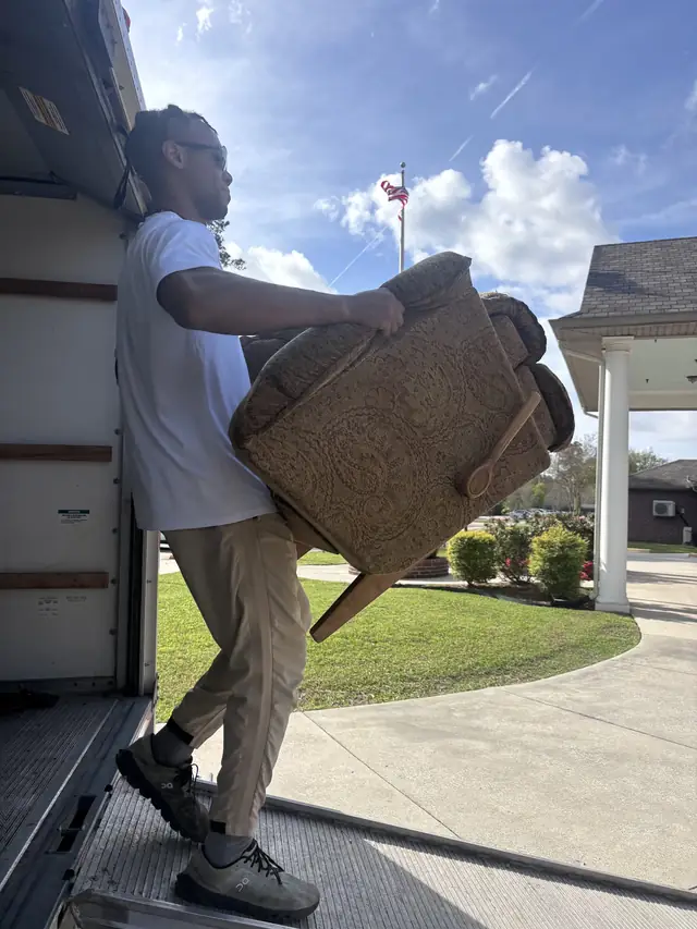Mover carrying an armchair down the truck ramp