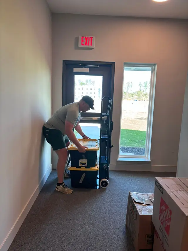 Mover stacking totes on a dolly in a hallway