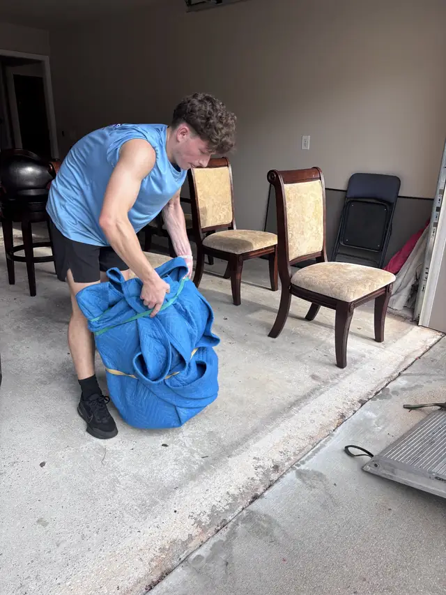 Mover folding blue moving blankets in a garage