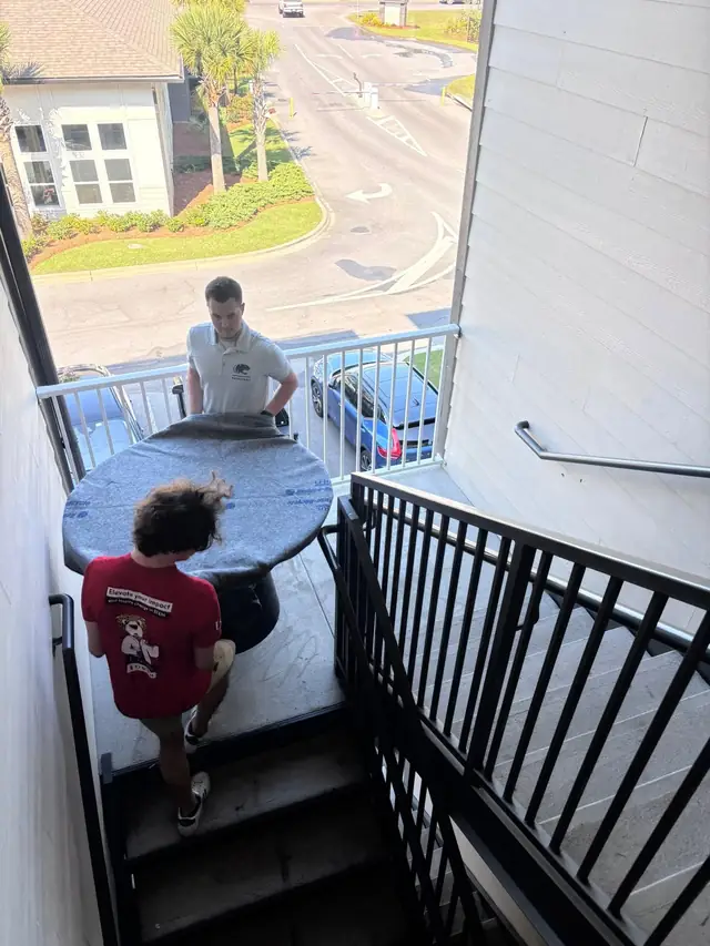 Movers carrying a table up exterior apartment stairs