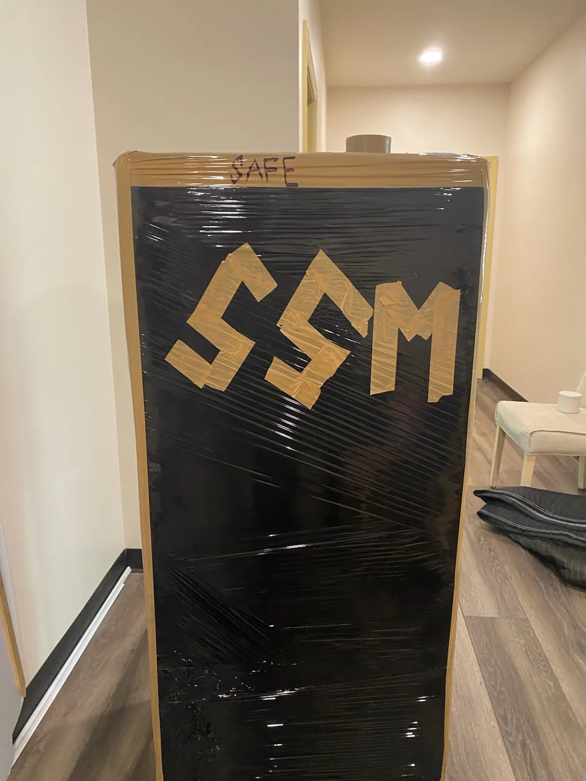 Safe protected with black stretch wrap and marked SSM for a Southern Shores Moving job