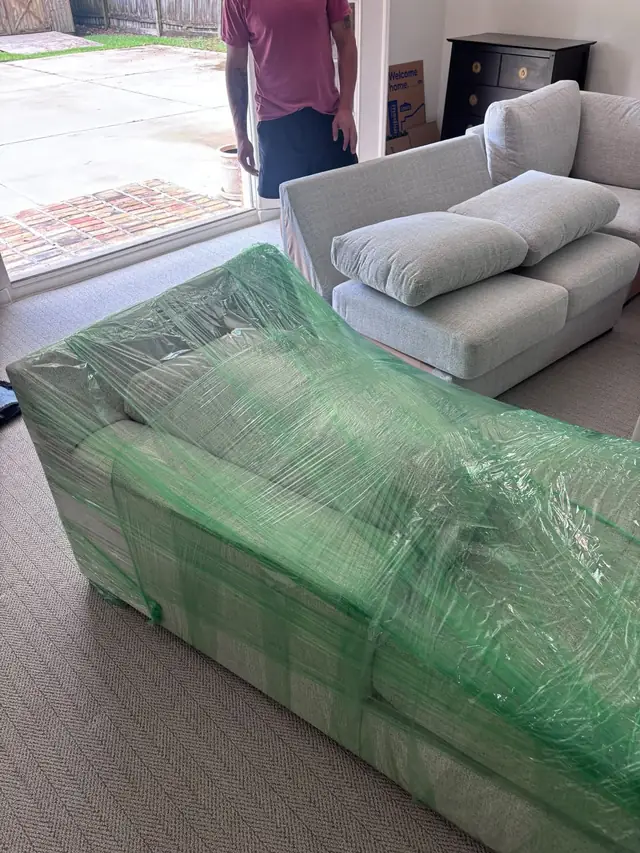 Sectional sofa wrapped in moving blankets and plastic