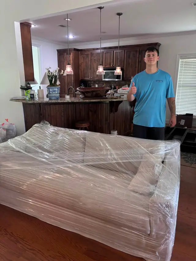 Mover next to a shrink-wrapped sofa in a kitchen