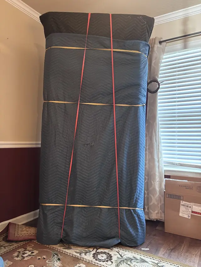 Tall item wrapped in blankets and secured with straps