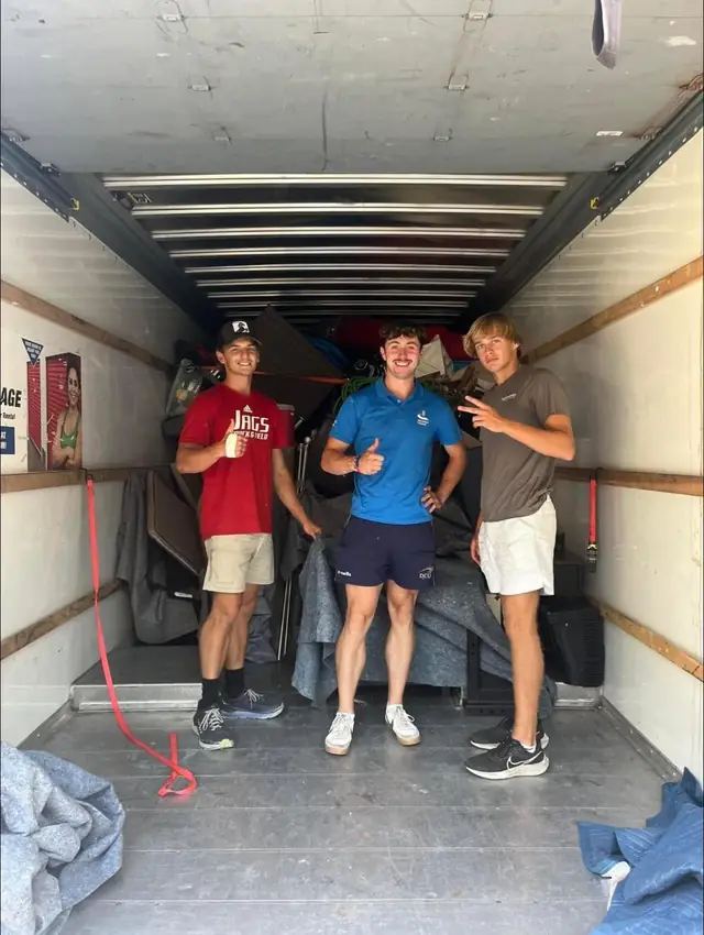 Three Southern Shores movers smiling inside a loaded box truck