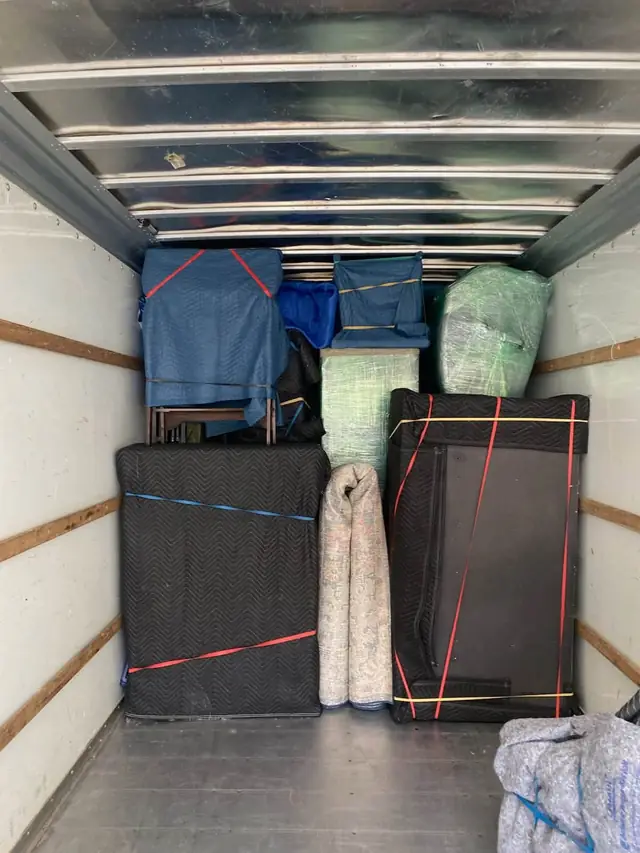 Box truck loaded with wrapped furniture and a mattress